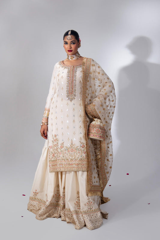 Woman in white and gold embroidered Pakistani bridal outfit with dupatta
